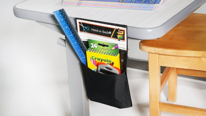 Black Hand-e-Sack hanging from side of desk with school supplies